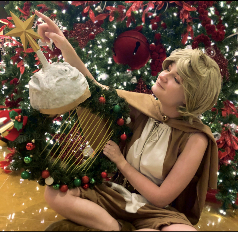 SINoALICE Pinocchio Christmas cosplayer holding a reef with a gray molded moon head.
